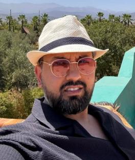 Man wearing a hat and sunglasses outdoors.