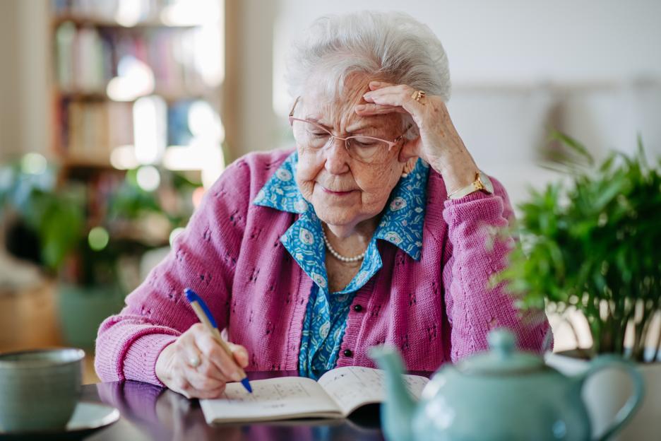 Elderly woman solving a Sudoku puzzle.