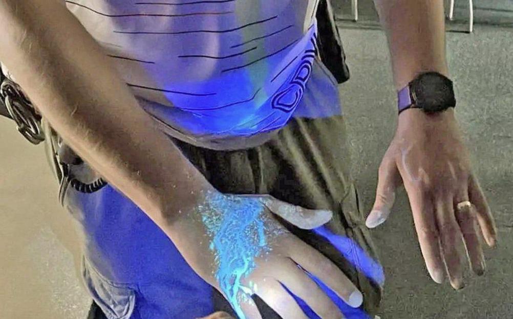DNA tagging spray applied to a hand, glowing under UV light.