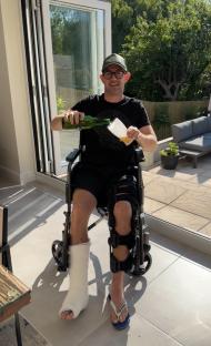 Man in wheelchair with leg cast pouring a drink.