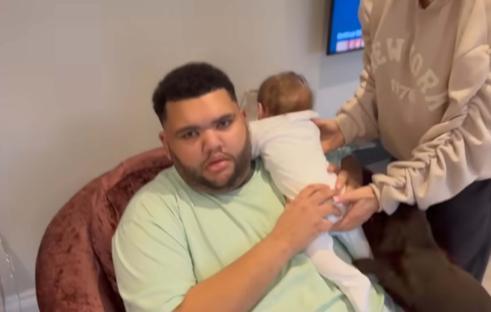 A man holds a baby while a woman helps adjust the baby's clothing.