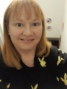 Selfie of a woman wearing a black shirt with yellow Playboy bunnies.