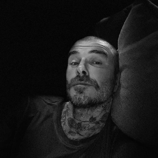 Black and white photo of David Beckham with a shaved head.