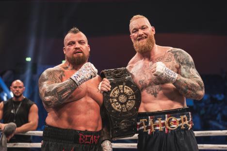 Eddie Hall and Hafþór Björnsson holding a boxing championship belt.