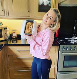Woman in pink holding a loaf of bread in her kitchen.