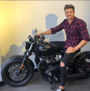 Man sitting on a black Triumph motorcycle.