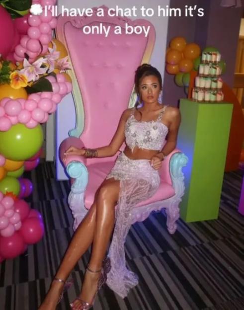 Venezuela Fury seated on a pink throne chair in a white and silver embroidered two-piece outfit.