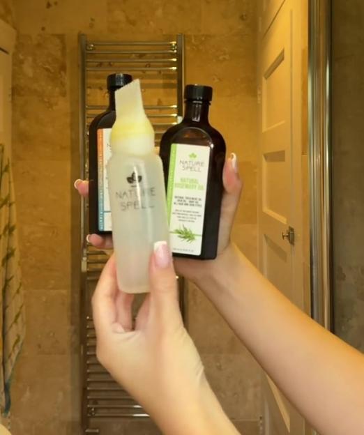 Hands holding two Nature Spell hair products, a Natural Rosemary Oil and another product in a clear bottle with a comb applicator.