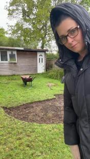 Woman in a garden preparing a fire pit area.