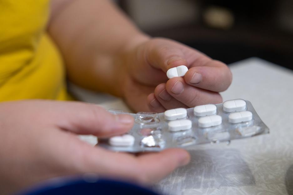 Woman's hands holding a pill and blister pack of pills.