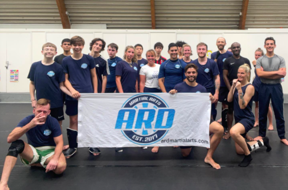 Group photo of martial arts students and instructors holding a banner for ARD Martial Arts.