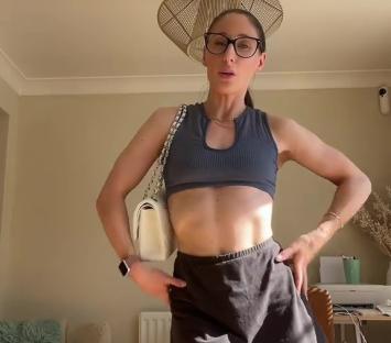 Woman in a gray crop top and black mini skirt, holding a white handbag.