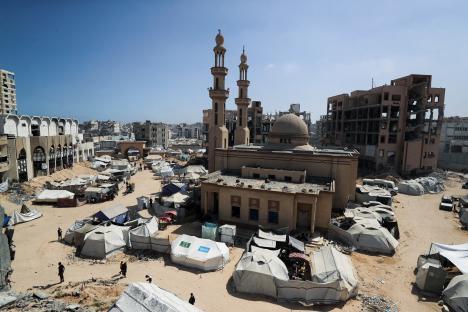 Displaced Palestinians in Gaza City sheltering in tents amidst damaged buildings.