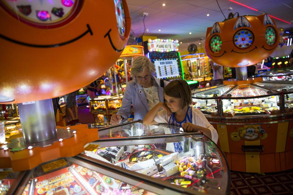 A young girl and an elderly woman play a 2p slot machine in an amusement arcade.