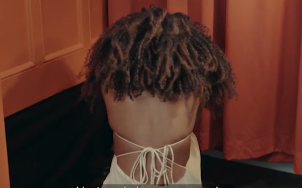 The back of a person wearing a white dress with a crisscross tie-up detail.