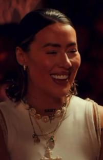 Demi Sims smiling and wearing layered necklaces.
