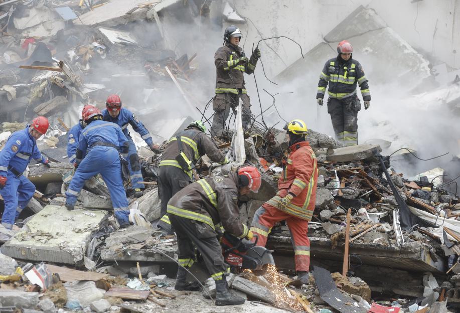 Rescue workers clearing debris from a damaged building.