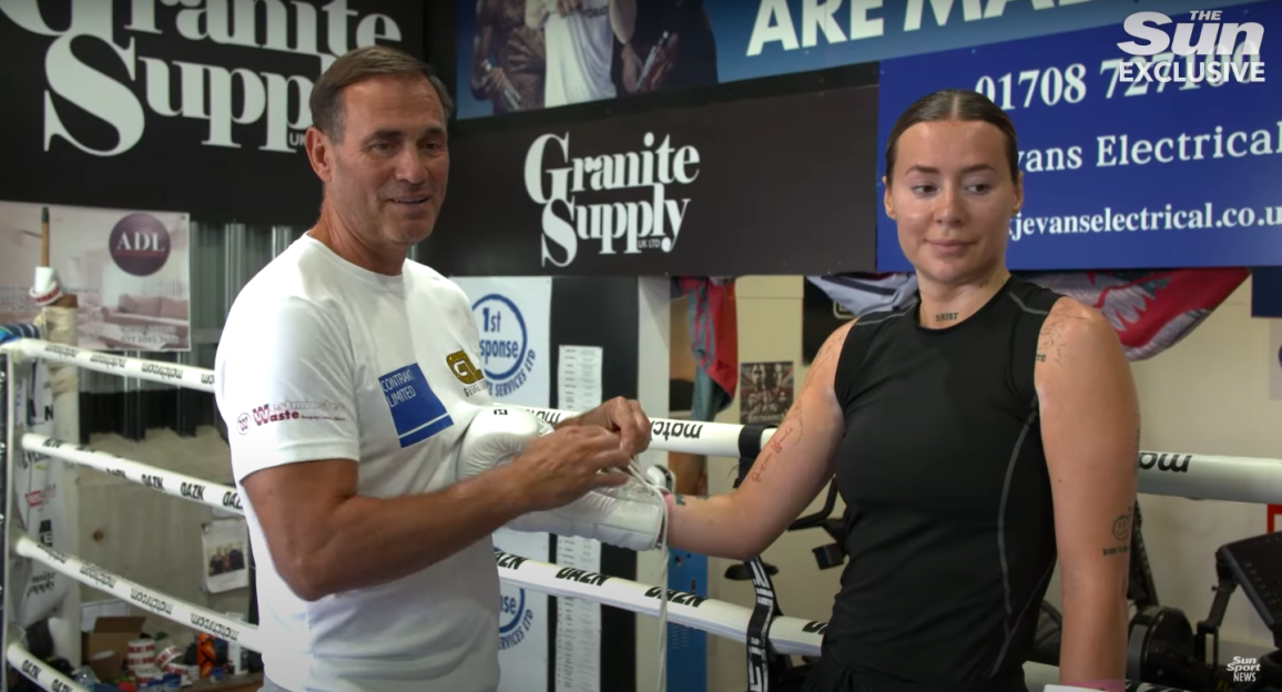 A man helps a woman put on boxing gloves.