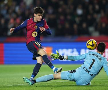 Pau Victor of FC Barcelona shoots at goal, while Sergio Herrera of CA Osasuna makes a save.