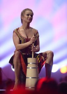 A dancer in traditional Polish costume using a butter churn during a performance.