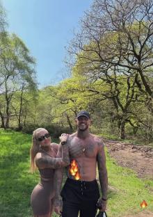 Couple posing outdoors in a wooded area.