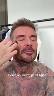 David Beckham having makeup applied by someone off-camera.
