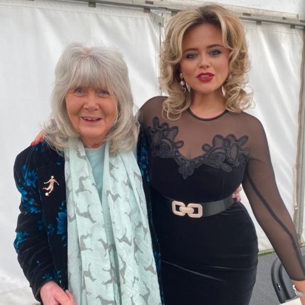 Emily Atack and Jilly Cooper posing together with their arms around each other.