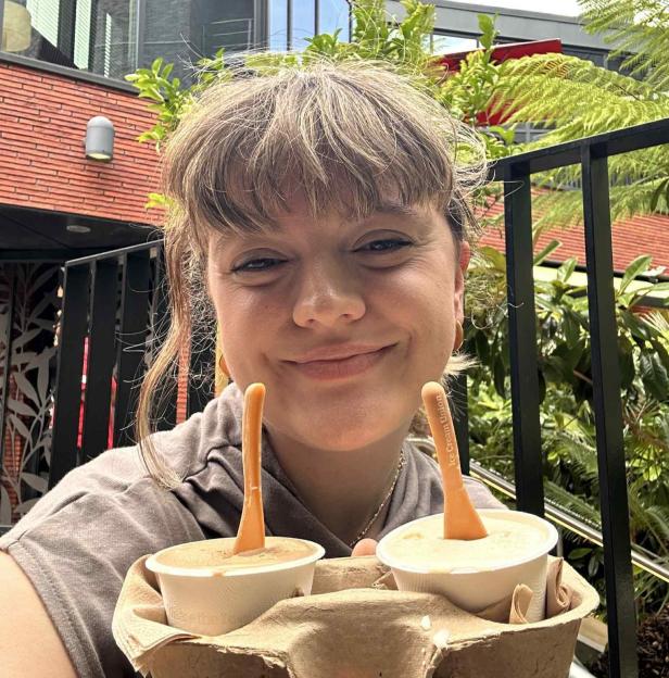 Person holding two cups of ice cream.