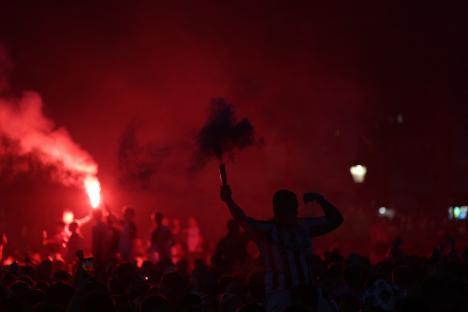 Sunderland fan holding a flare amidst a crowd.