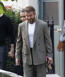 David Beckham carrying a bottle of wine, walking with a woman.
