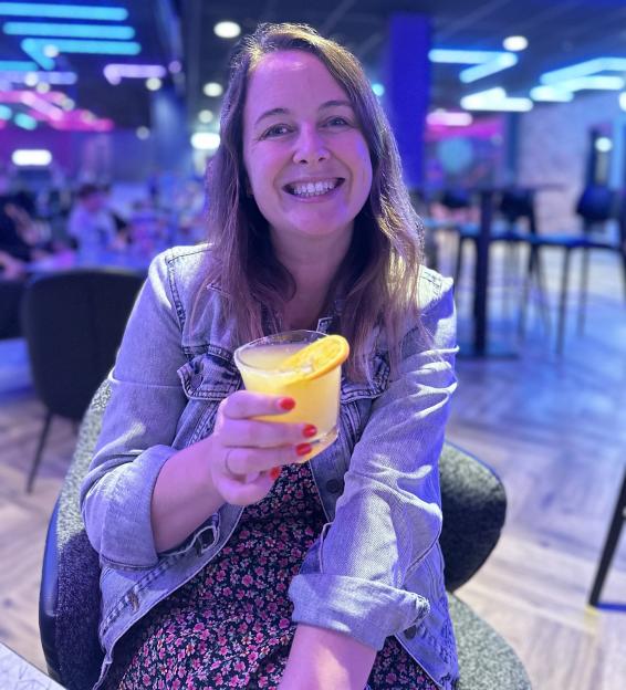 Woman smiling and holding a cocktail in a bar.