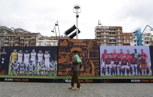 Person walking past billboards of Tottenham Hotspur and Manchester United soccer teams in Bilbao, Spain.