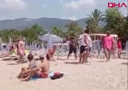 A person being attacked on a crowded beach.