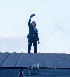 Tom Cruise taking a selfie on a rooftop.