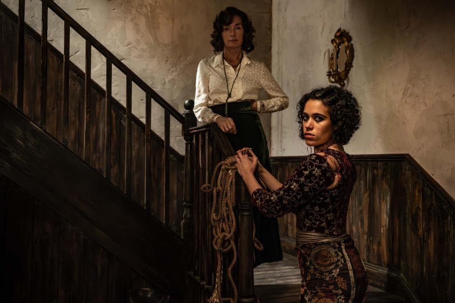 Two women on a staircase, one holding rope.