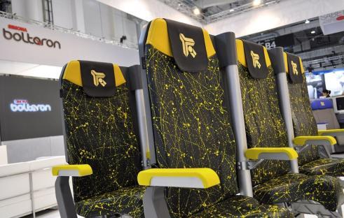 Stand-up airplane seats with yellow and black splatter design.