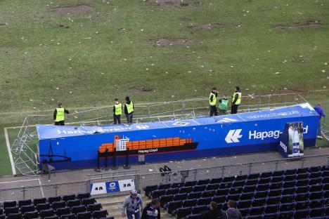 Stadium security personnel cleaning up litter after a soccer match.