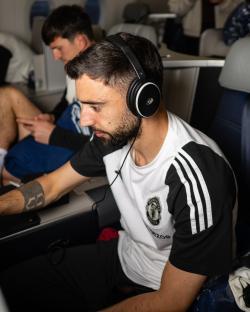 Bruno Fernandes of Manchester United wearing headphones on a plane.