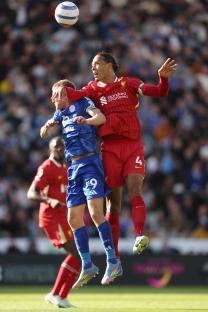 Virgil van Dijk of Liverpool jumping for a header during a soccer match.