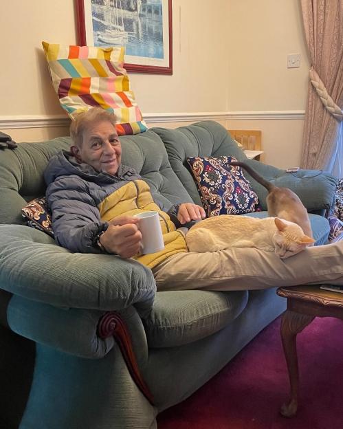 Sid Siddiqui sitting on a couch with two cats.