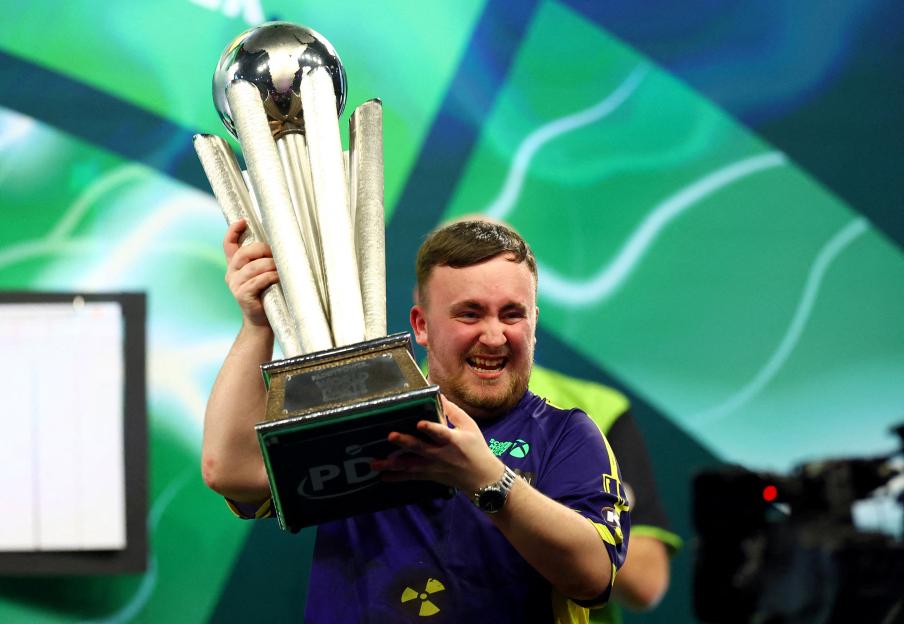 Luke Littler holding the PDC World Darts Championship trophy.