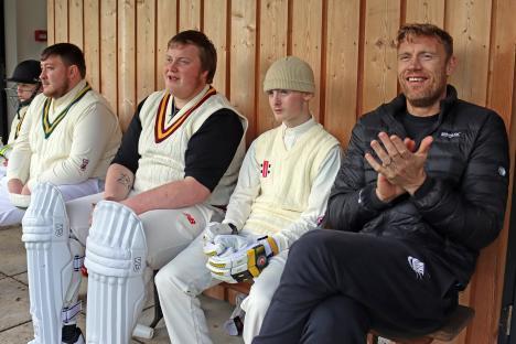 Cricket players and Freddie Flintoff sitting on a bench.