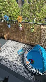 Balcony makeover with potted plants, windmills, and a child's inflatable pool.