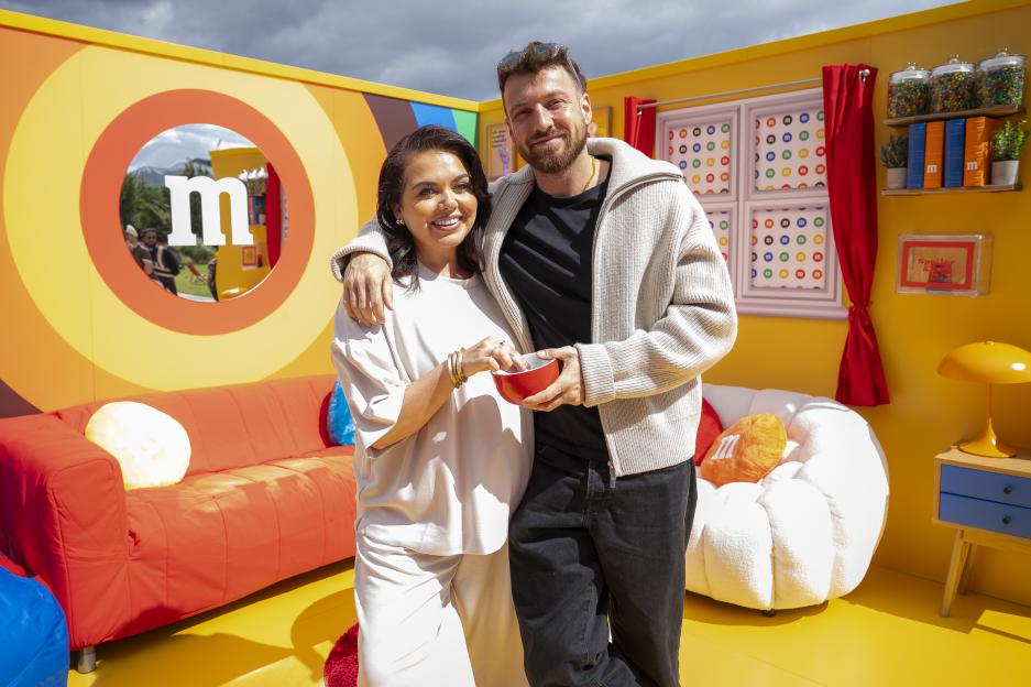 Two people posing on an M&M's branded couch.