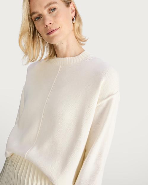 Woman wearing a cream-colored knit sweater.