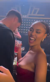 Woman in red dress holding a drink and smiling.