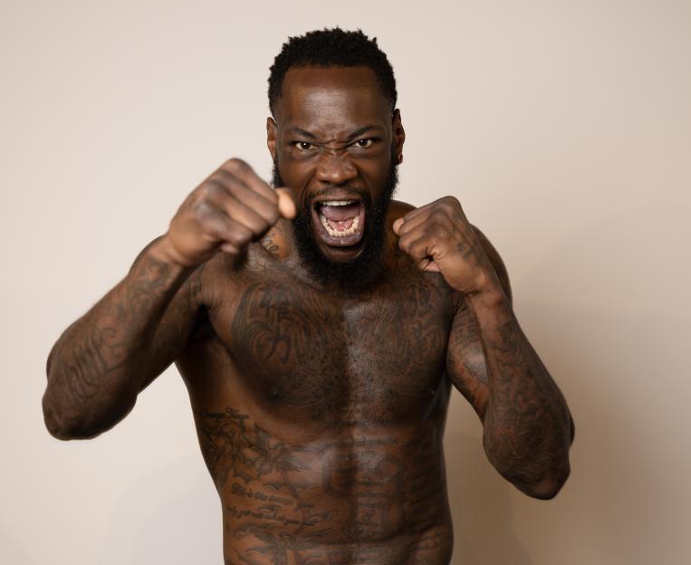 Boxer Deontay Wilder shouts while posing with fists raised.
