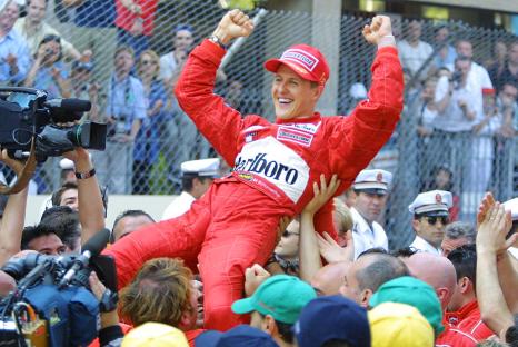 Michael Schumacher being lifted by his mechanics after winning a Formula One race.