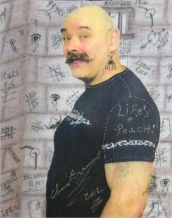 Portrait of Charles Bronson, British criminal, against a background of prison wall graffiti.