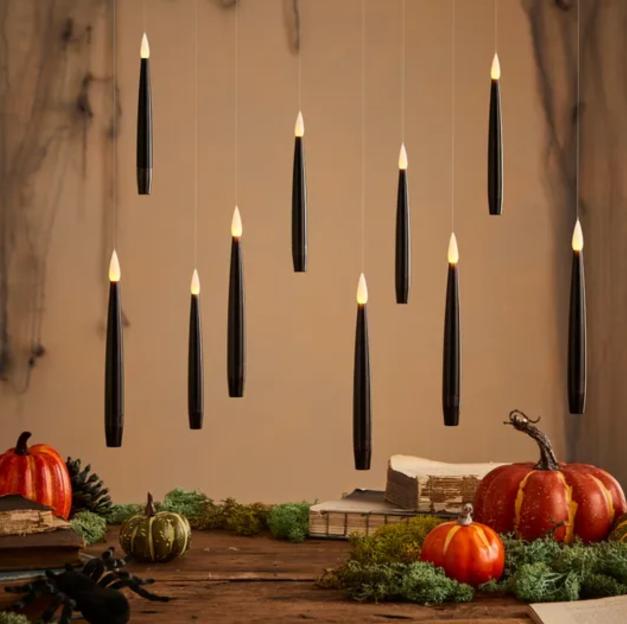 Black LED candle lights hanging above pumpkins and books.
